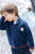 Child wearing a blue cardigan with a logo, 