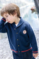 Child wearing a blue cardigan with a logo, 