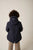Person wearing a dark blue hooded jacket on a beige background