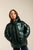 Child wearing a green puffer jacket on a plain background