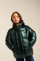 Child wearing a green puffer jacket on a plain background